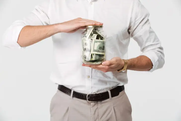 Man holding jar filling with cash